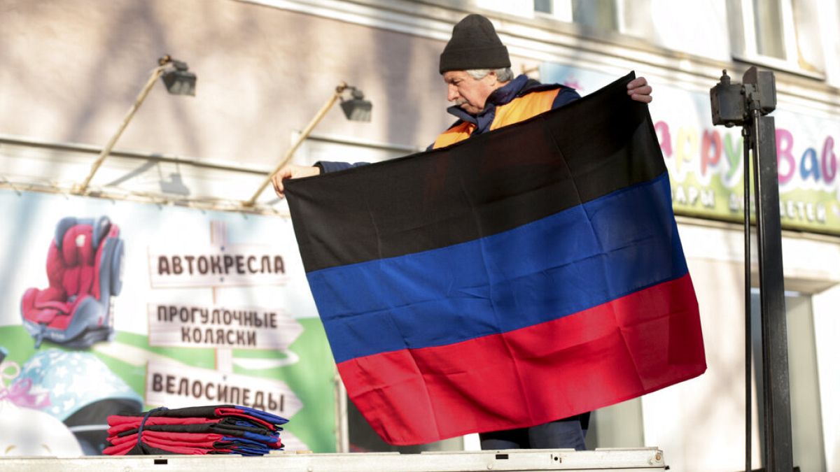Ukrayna'nın doğusunda bir kişi "Donetsk Halk Cumhuriyeti" bayrağını binaya asıyor. 21 Şubat 2022