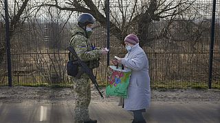 A Ukrainian serviceman checks the documents of a woman crossing to government controlled areas from pro-Russian separatists controlled territory in Stanytsia Luhanska