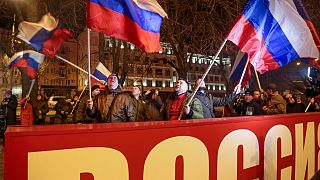 Menschen schwenken russische Nationalflaggen und feiern hinter einem Transparent mit der Aufschrift "Russland" im Zentrum von Donezk, 