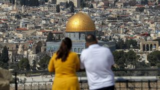 صورة تم التقاطها من جبل الزيتون في 18 فبراير 2022  وتظهر ساتحين يلتقطان الصور لمدينة القدس القديمة وقبة الصخرة في مجمع المسجد الأقصى