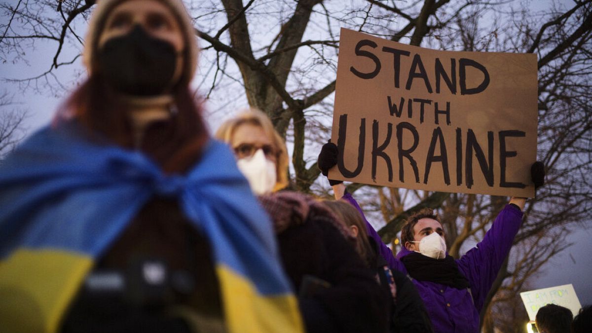 A man holds a poster in support of Ukraine as he attends a demonstration near the Russian embassy 