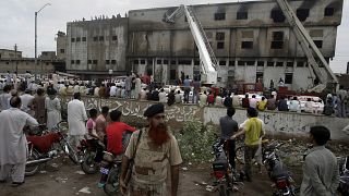 People gather at the site of burnt garment factory in Karachi, Pakistan on Wednesday, Sept. 12, 2012. 