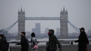 Workers walk over London Bridge towards the City of London financial district.