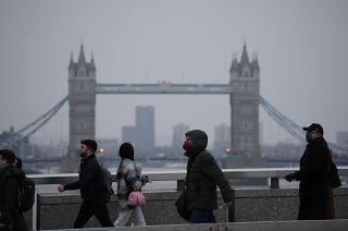 Workers walk over London Bridge towards the City of London financial district.