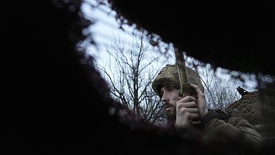 A Ukrainian service member listens to artillery shots standing in a trench on a position at the line of separation near Zolote