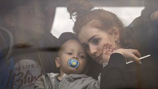A woman holds her baby inside a bus as they leave Kyiv, Ukraine, Thursday, Feb. 24, 2022.