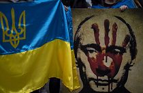 A protestor holds a banner depicting Russian President Vladimir Putin during a demonstration in front of the Russian Embassy in Madrid, Spain, Thursday, Feb. 24, 2022.