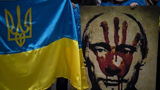 A protestor holds a banner depicting Russian President Vladimir Putin during a demonstration in front of the Russian Embassy in Madrid, Spain, Thursday, Feb. 24, 2022.