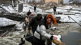 Civilians cross a river on a blown up bridge on Kyiv's northern front on March 1, 2022