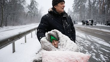 An elderly woman is coated in snow as she sits in a wheelchair after being evacuated from Irpin, on the outskirts of Kyiv, Ukraine. March 8, 2022