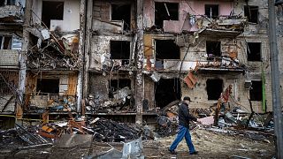 A man walks past a building damaged following a rocket attack the city of Kyiv, Ukraine, Friday, Feb. 25, 2022.