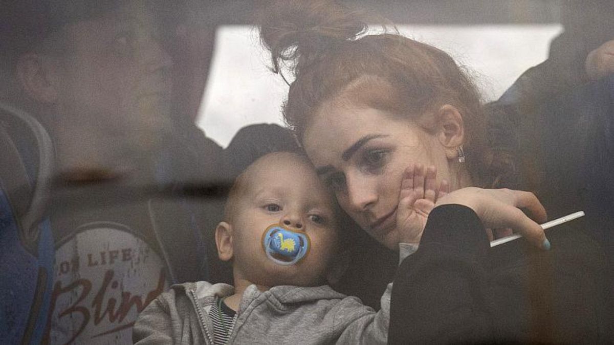 سيدة تحمل طفلها داخل حافلة أثناء مغادرتهم كييف