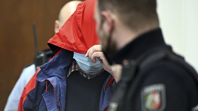The 70-year-old priest is led into the courtroom in Cologne.