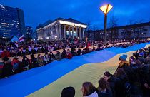 People carry a giant flag of Ukraine to demonstrate against Russian attacks in Ukraine at Independence Square in front of the Parliament Palace in Vilnius, Lithuania