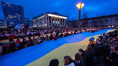 People carry a giant flag of Ukraine to demonstrate against Russian attacks in Ukraine at Independence Square in front of the Parliament Palace in Vilnius, Lithuania