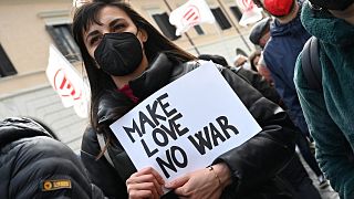 Un manifestant tient une pancarte sur laquelle on peut lire "Make love no war" lors d'une manifestation organisée par les associations italiennes du Réseau pour la paix .