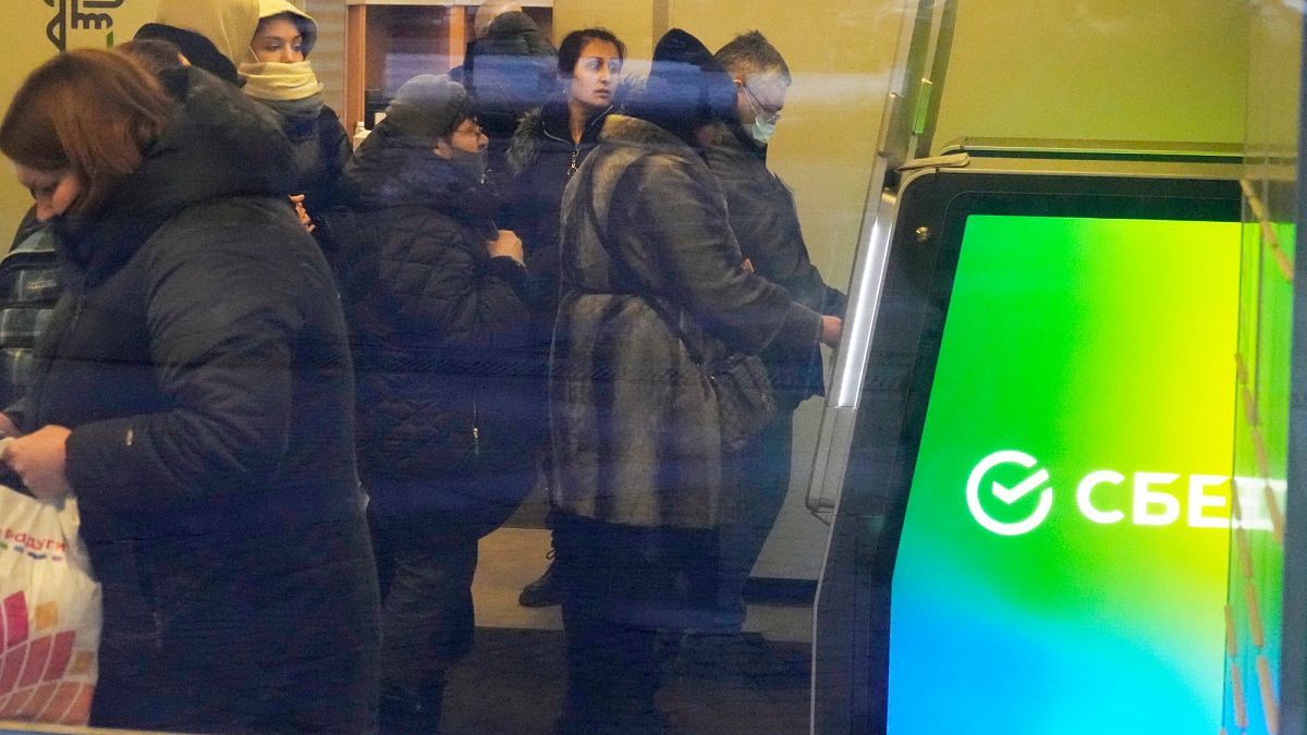 Жители Санкт-Петербурга снимают деньги в банкоматах "Сбербанка".