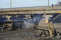 Ukrán katona egy kiégett katonai jármű mellett