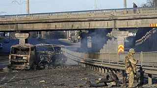 Ukrán katona egy kiégett katonai jármű mellett