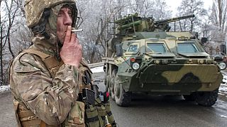 Um soldado ucraniano fuma um cigarro ao pé de um veículo blindado nos arredores de Kharkiv