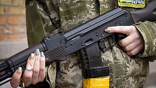 Una mujer de la defensa civil armada sostiene un fusil de asalto Kalashnikov mientras patrulla una calle vacía debido al toque de queda en Kiev
