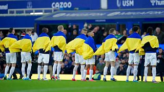 Everton players hold Ukrainian flags before the English Premier League soccer match