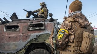 Украинские солдаты под Харьковом осматривают сгоревшую российскую бронемашину