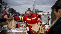 Un empleado de los servicios de emergencia rumanos reparte bolsas de comida a los refugiados que huyen de Ucrania