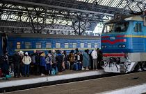 People trying to flee Ukraine stand on a platform as they wait for trains inside Lviv railway station.