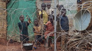 أسرة تقف خلف الأسلاك الشائكة التي تحيط بالمخيم المحمي من قبل الأمم المتحدة، لحمايتها في جنوب السودان