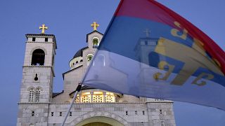An opposition supporter waves an old Serbian flag during a protest in front of an Orthodox Church in Montenegro in 2020.