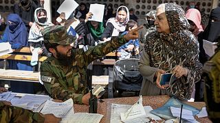 یک زن مسن افغان در اداره گذرنامه در حال صحبت با مامور طالبان، اکتبر ۲۰۲۱