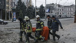 Personnels de secours ukrainiens transportant le corps d'une victime du bombardement russe ayant touché le centre-ville de Kharkiv, le 01/03/2022