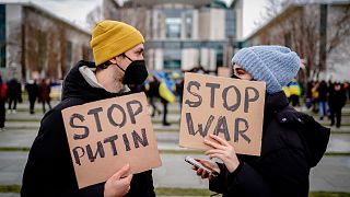 People hold banners during a demonstration in front of the Federal Chancellery, in Berlin, Thursday Feb. 24 2022, following the Russian attack of Ukraine