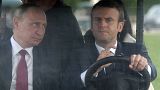 French President Emmanuel Macron, right, drives an electric golf car with Russian President Vladimir Putin in the garden of the Versailles Palace in 2017.