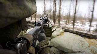 جندي روسي يصوب سلاحه من شاحنة عسكرية روسية أثناء سيرها تجاه مكان مجهول في أوكرانيا
