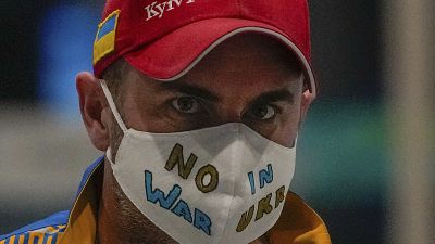 A Ukrainian journalist wearing a face mask bearing the words "No War in Ukraine" walks through the Main Media Center ahead of the 2022 Winter Paralympics in Beijing, China