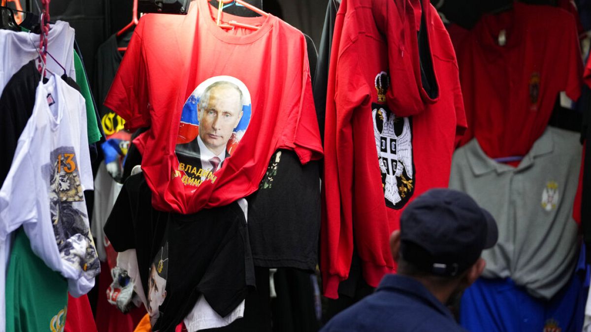 A man looks at a shirt with a picture of Russian President Vladimir Putin displayed on Belgrade's main pedestrian street, Serbia, Saturday, Feb. 26, 2022.