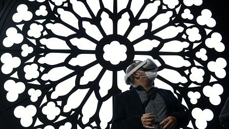 A man uses a virtual reality glasses at the stand of Orange to visit Notre Dame Cathedral at the MWC (Mobile World Congress) in Barcelona on March 2, 2022.