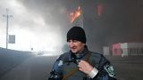 A Ukrainian serviceman walks as fire and smoke rise over a building following shelling in Kyiv, Ukraine, March 3, 2022.