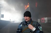 A Ukrainian serviceman walks as fire and smoke rise over a building following shelling in Kyiv, Ukraine, March 3, 2022.