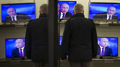 A man watches Russian President Vladimir Putin on TV screens in an electronic hypermarket in Moscow,, 2014 A man watches Russian President Vladimir Putin on TV screens in an electronic hypermarket in Moscow,, 2014