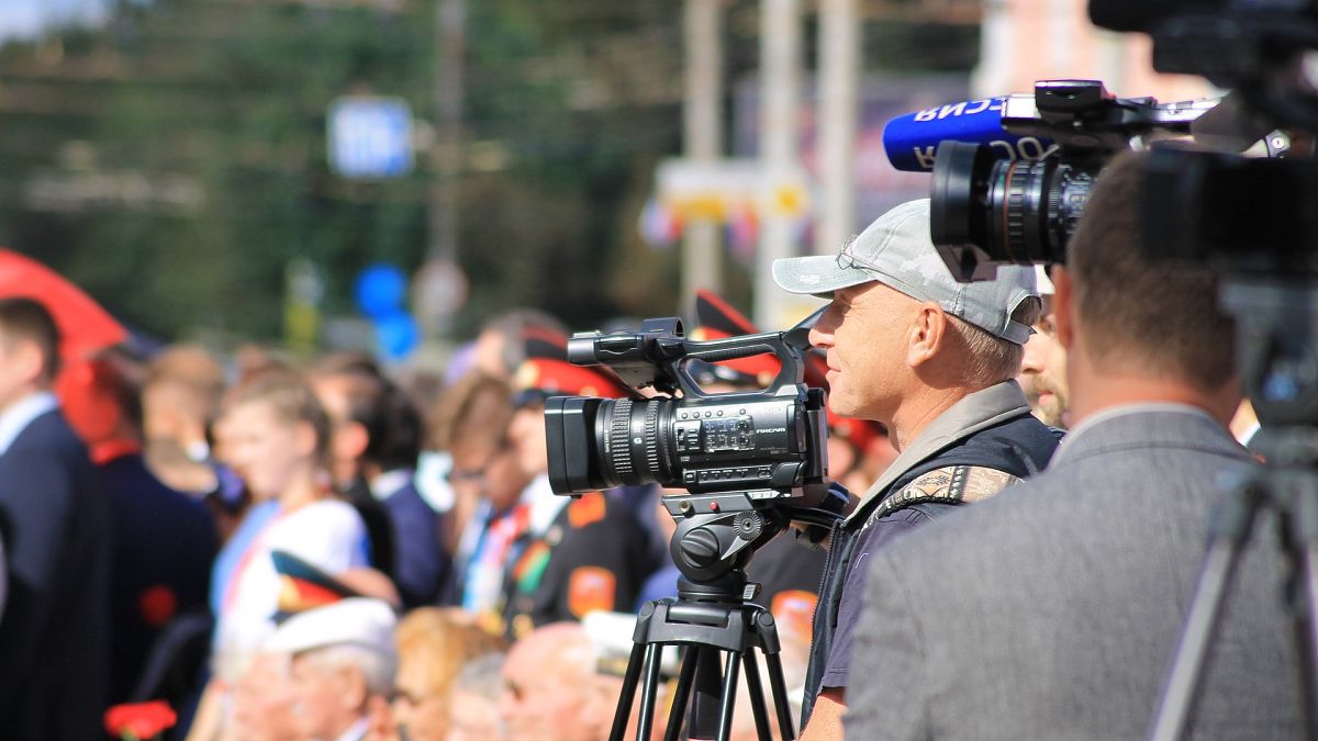 صورة لصحفي يقف خلف كاميرته وسط حشد من الناس 