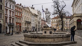 Un homme se tient à côté d'une sculpture recouverte d'une bâche dans le centre-ville de Lviv, dans l'ouest de l'Ukraine, vendredi 4 mars 2022.