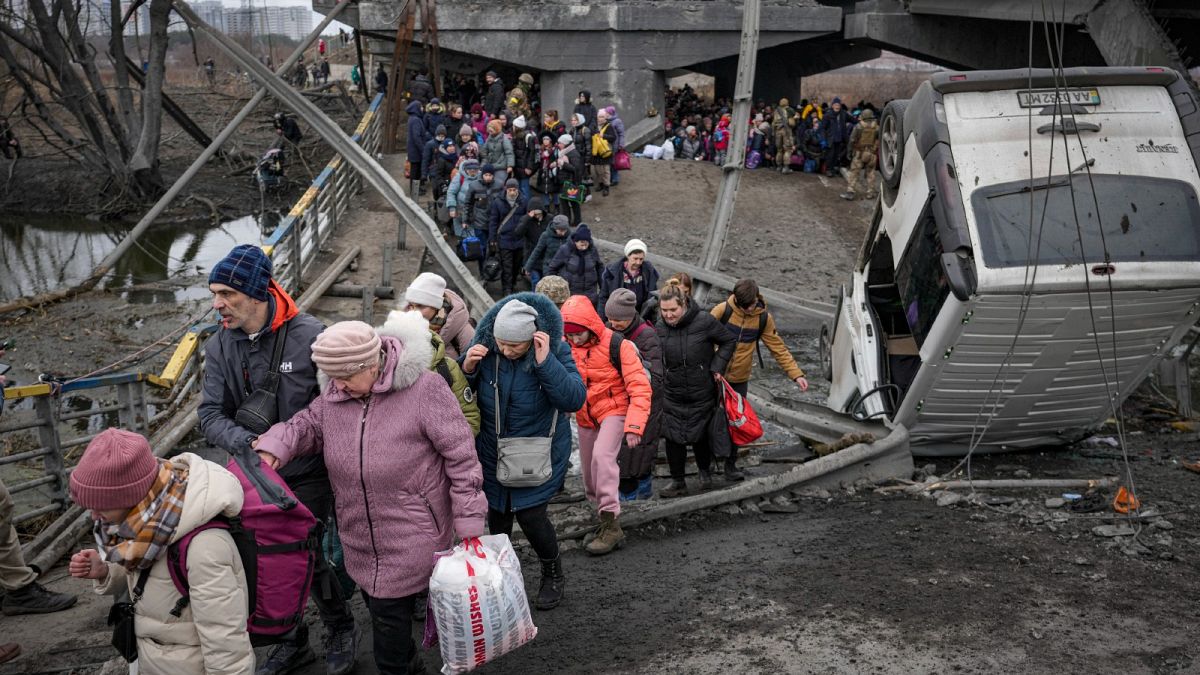 People cross on an improvised path under a bridge that was destroyed by a Russian airstrike, while fleeing the town of Irpin, Ukraine, March 5, 2022. 