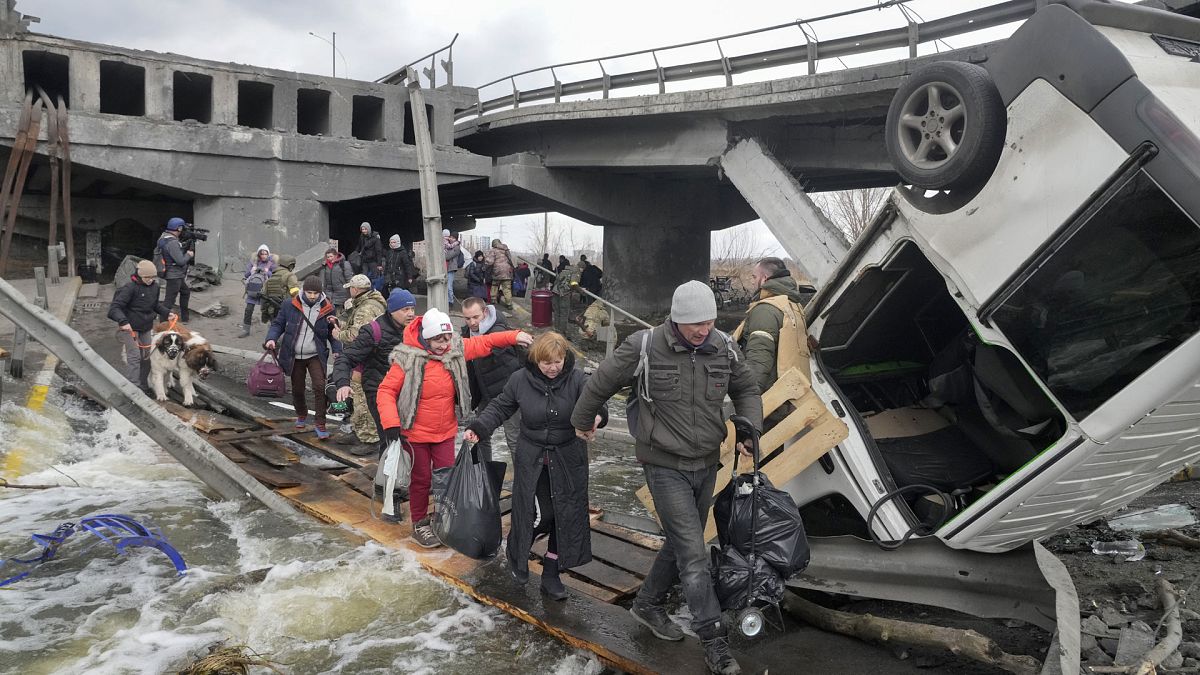 Des personnes fuyant la ville d'Irpin, près de Kiev, sur un pont improvisé, le lundi 7 mars 2022. 