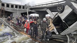 Des personnes fuyant la ville d'Irpin, près de Kiev, sur un pont improvisé, le lundi 7 mars 2022.