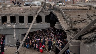 Des civils ukrainiens se pressent sous un pont détruit alors qu'ils tentent de fuir en traversant la rivière Irpin dans la banlieue de Kiev, en Ukraine, samedi 5 mars 2022