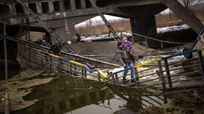 Local militiaman Valery, 37, carries a child as he helps a fleeing family across a bridge destroyed by artillery, on the outskirts of Kyiv, Ukraine, Wednesday, March 2. 2022 Local militiaman Valery, 37, carries a child as he helps a fleeing family across a bridge destroyed by artillery, on the outskirts of Kyiv, Ukraine, Wednesday, March 2. 2022