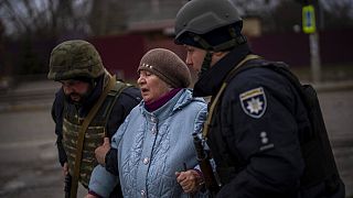 ضباط الشرطة الأوكرانية يساعدون امرأة على الهرب بينما يتردد أصداء المدفعية في مكان قريب في إيربين، في ضواحي كييف، أوكرانيا، يوم الاثنين 7 مارس 2022